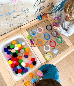 two children are playing with their toys on the floor in front of an art table