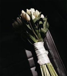 a bouquet of white tulips tied to a black suitcase