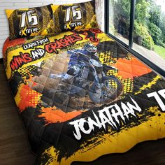 a bed covered in a yellow and black comforter with an image of a motorcycle on it