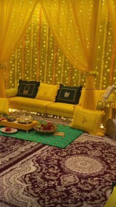 a living room decorated in yellow and red with lights on the walls, couches and rugs