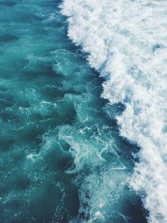 the wake of a boat in the ocean with blue and green water, taken from above