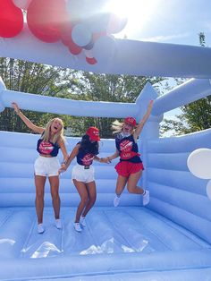 three girls jumping on an inflatable slide