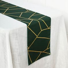 a white table topped with a green and gold table runner on top of a white table cloth