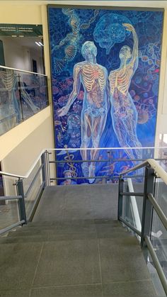 a large painting on the wall in a building with glass railings and handrails