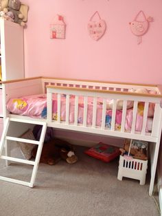 a child's bedroom with pink walls and white bunk bed, toys on the floor