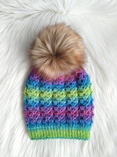 a multicolored knitted hat with a pom - pom on top