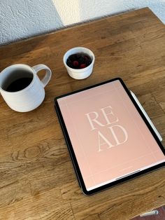 a tablet computer sitting on top of a wooden table next to two cups of coffee