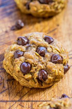 two chocolate chip cookies sitting on top of a wooden table