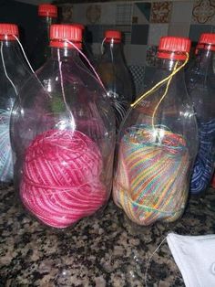 three bottles with yarn in them sitting on a counter