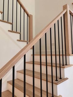 a wooden stair case with black handrails in a home's entryway