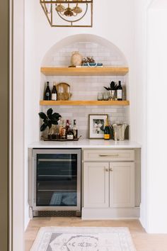 a kitchen with white cabinets and shelves filled with bottles, wine glasses and other items