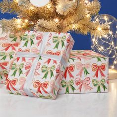 two wrapped presents under a christmas tree with lights on the branches in front of it