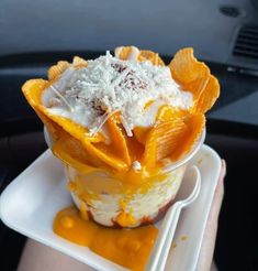 a person holding up a plastic container with food in it on top of a plate