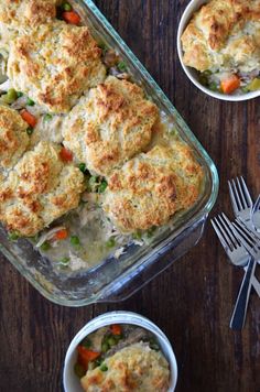 a casserole dish with chicken and vegetables in it on a wooden table next to silverware