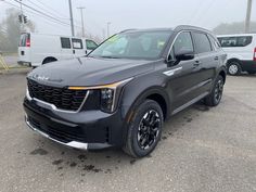 a gray suv parked in a parking lot next to other cars and trucks on a foggy day