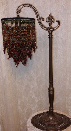 a lamp with beads hanging from it's side next to a wallpapered background