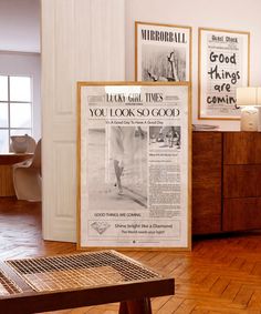 there is a newspaper on the floor next to a wooden table and two framed pictures