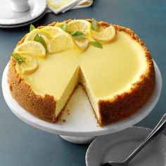 a lemon cheesecake on a plate with a slice cut out and ready to be eaten