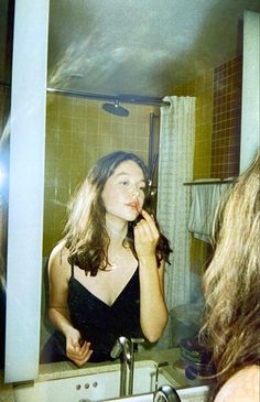 a woman brushing her teeth in front of a mirror