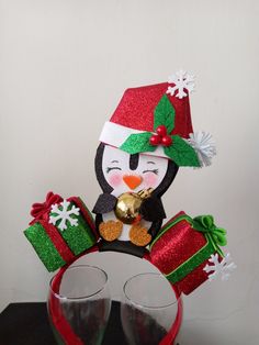 two wine glasses and a penguin figurine with christmas decorations on them sitting next to each other