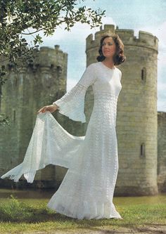 a woman in a white dress is standing near a castle