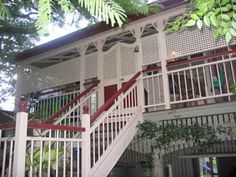 a white house with red railings and stairs leading up to the second story area