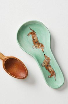 a spoon with a dog design on it next to a wooden spoon that is shaped like a spoon