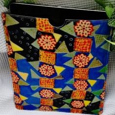 a colorful bag sitting on top of a white table next to a potted plant