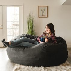 a woman sitting on a bean bag chair holding a cup