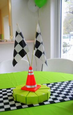 a small traffic cone on top of a green table cloth with two flags in the background