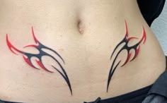 a woman's stomach with red and black tattoos on it