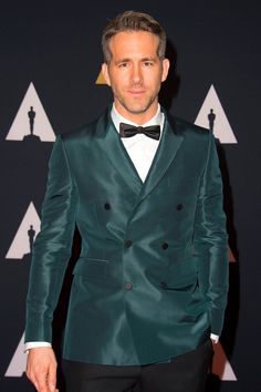 a man in a tuxedo and bow tie at an oscars event with his hands in his pockets