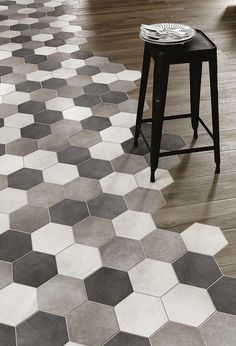 a black stool sitting on top of a hard wood floor next to a white table