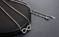 Centered between the two lengths of shiny silver tone chain, this miniature eternity symbol appears to float along the neck. Completely encrusted in micro CZ stones creating incredible shimmer. At only 2 cm this is truly subtle and graceful. This necklace is perfect for women, teens or young children. Length: 18 inch chain Stones: CZ Metal: Sterling Silver, 3 layers of platinum plating. Comes in a gift box. (Reg $45.99) Infinity Symbol Necklace, Eternity Symbol, Eternity Necklace, Necklace Infinity, Symbol Necklace, Infinity Symbol, Shiny Silver, 3 Layers, Micro Pave