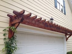 a wooden trellis attached to the side of a house next to a white garage