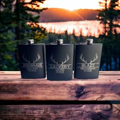 three black flasks sitting on top of a wooden table