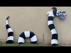 two large black and white striped sculptures next to a wall with a dragon on it