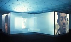 an empty room with three large screens on the wall and one man's face