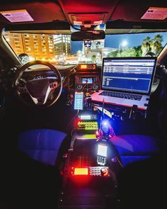 the interior of a vehicle with multiple electronic devices on the dashboard and two laptops in the passenger seat