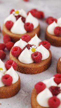 small desserts with raspberries and whipped cream on them are arranged in rows