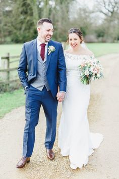 a bride and groom walking down a dirt road