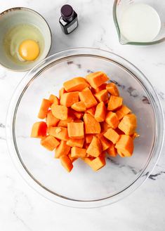 chopped up carrots in a glass bowl next to an egg on a marble counter top