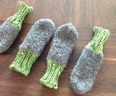 three knitted mittens sitting on top of a wooden table