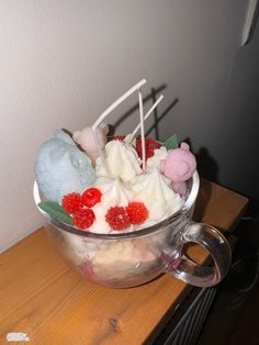 a glass bowl filled with ice cream and raspberries on top of a wooden table