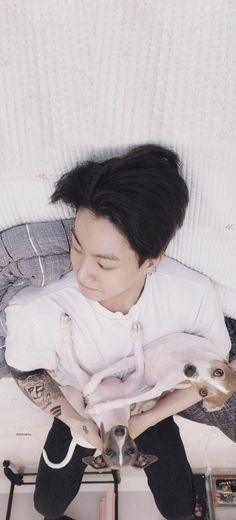 a young man sitting on top of a bed holding two small deer statues in his hands