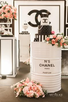 a chanel cake sitting on top of a table next to flowers and vases