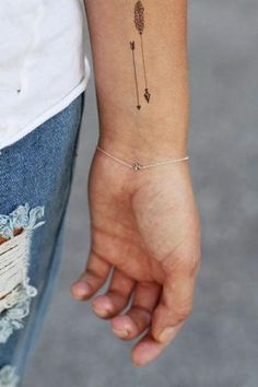 a woman's arm with an arrow tattoo on the left side of her wrist