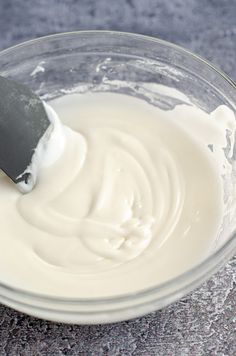 a glass bowl filled with yogurt and a knife sticking out of the top