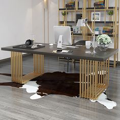 a desk with a cow hide rug on the floor in front of it and a bookcase behind it