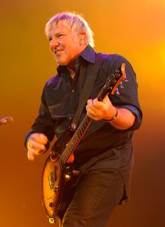 a man with blonde hair playing an electric guitar